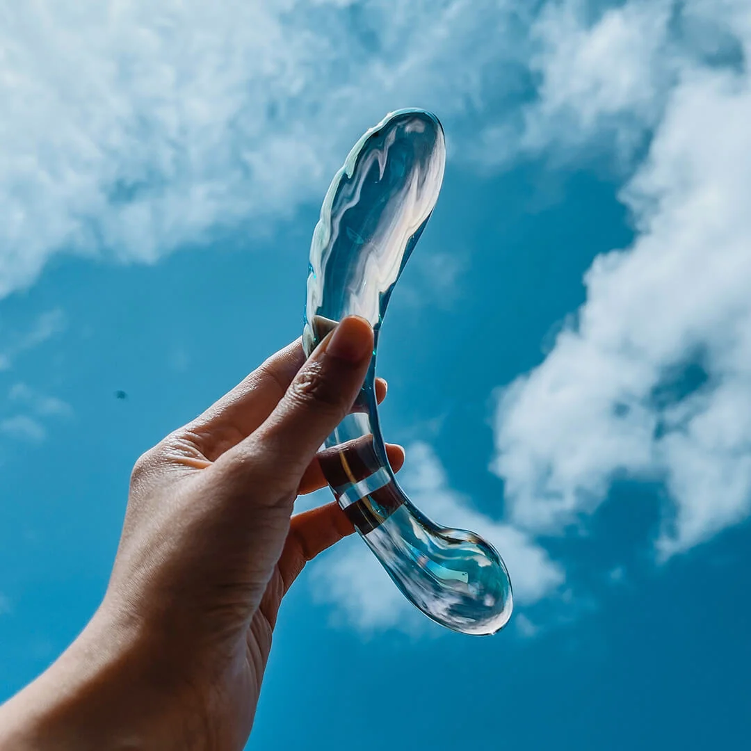 Biird glass wand held against a blue sky and white clouds